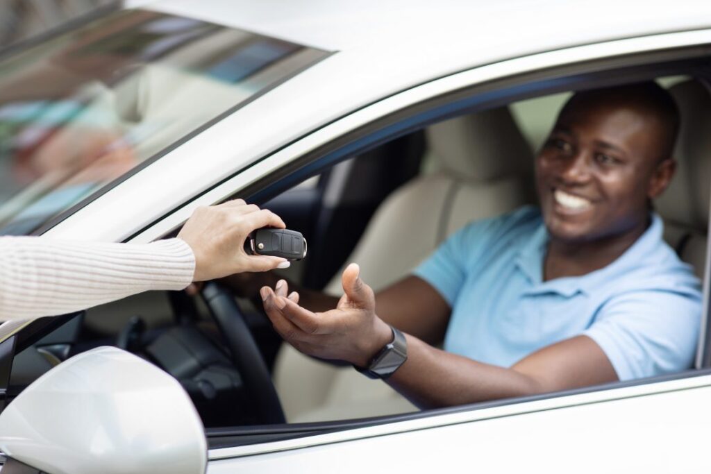 black man taking key from auto renting car for trip